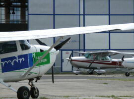 Hanger mit Flugzeugen auf dem Kamenzer Flugplatz. Links im Vordergrund ist seitig ein Segelflugzeug mit dem Logo MDR Radio Sachsen zu sehen. Rechts im Hintergrund weitere Flugzeuge. Beispielbild für Freizeiteinrichtungen in Kamenz.