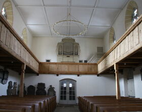 Innenraum der St. Just-Kirche mit Orgel im Mittelpunkt, rechts und links befinden sich die Sitzbänke. 
