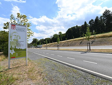 Parkplatz auf der Königsbrücker Straße am Hutberg in Kamenz. Beispiel für Parkplatz für Reisebusse. Links Schild mit Lessing-Figur und der Aufschrift Willkommen in Kamenz als touristische Ortseingangstafel.