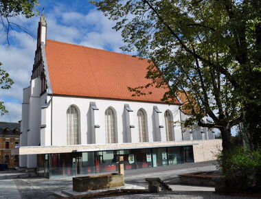 Seitlicher Blick auf die Kamenz-Information und Klosterkirche St. Annen, Schulplatz und Brunnen im Vordergrund. 