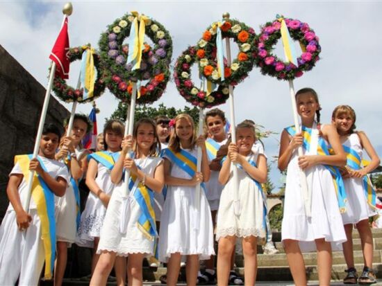 Traditionell gekleidete und geschmückte Kinder zum Kamenzer Forstfest. Sie tragen weiße Kleidung, bunte Schärpen, Blumenschmuck und Fahnen und lächeln nebeneinander in die Kamera. Beispiel für Forstfest Veranstaltung.