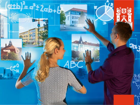 Imagebild der Kampagne Neue Stadt. Neues Glück zum Thema Bildung und Lernen. Zwei junge Erwachsene verschieben Bilder von Schulen auf einer virtuellen Tafel mit Buchstaben und mathematischen Formeln darauf.. 