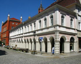 Arkadengang der Fleischbänke an der Kirchstraße. Ein historisches Gebäude mit Säulen, Runddurchgängen und Tierköpfen sowie Fleischerhaken an der Außenwand. Früher Fleischverkaufsstände. Beispiel für Sehenswürdigkeit in Kamenz.