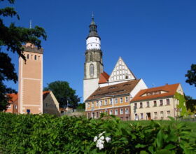 In der Mitte die Hauptkirche St. Marien mit Kirchturm. Davor Wohnhäuser. Links davon Roter Turm - ein Teil der ehemaligen Stadtbefestigung. Ansicht von der Pulsnitzer Straße aus im Sommer.