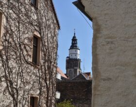 Blick durch zwei Häuser auf den Turm der Hauptkirche St. Marien
