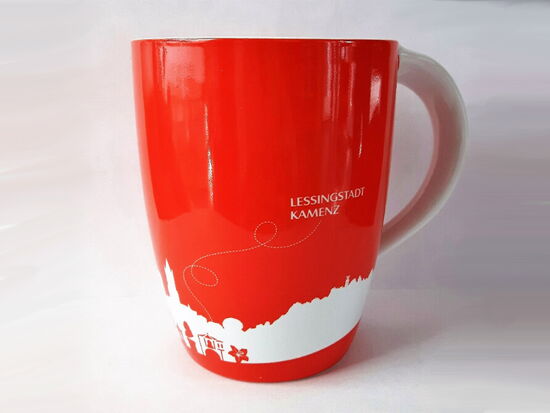 Exemplar einer Kamenz-Tasse in der Farbe rot mit weißer Schrift und Stadtsilhouette. Beispiel für Souvenirs und Geschenkartikel der Kamenz-Information.. 