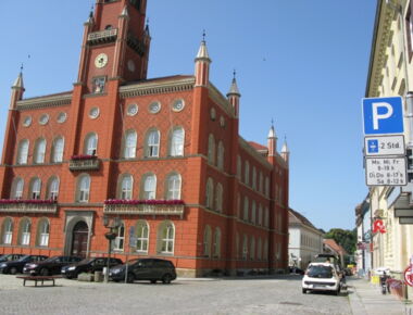 Kamenzer Marktplatz mit Parkflächen für PKW-Fahrer. Rechts im Vordergrund ist ein Schild, das auf die Parkmöglichkeit aufmerksam macht. Verschiedene Autos stehen dahinter auf Parkplätzen. Beispiel für Parkmöglichkeiten in Kamenz.