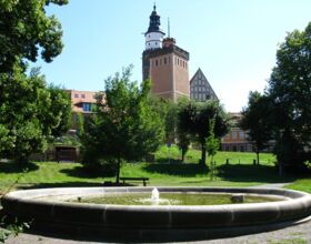 Brunnen der Schillerpromenade im Sommer, im Hintergrund Roter Turm und Turm der Hauptkirche St. Marien