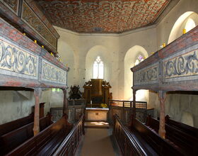 Innenansicht der Katechismuskirche, Sitzbänke rechts uns link mit jeweils kleiner Empore, Kanzel mit kleinem Altar in der Mitte. 