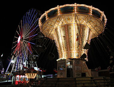 Rummelbetrieb auf dem Kamenzer Forstfest bei Nacht. Ein erleuchtetes Kettenkarussel dreht sich im Vordergrund. Im Hintergrund ein Riesenrad und kleinere Fahrgeschäfte. Beispiel für Veranstaltungen in Kamenz.. 