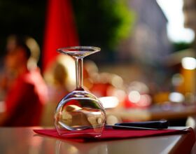 Weinglas umgedreht auf einem gedeckten Tisch mit Serviette und Besteck. Im Hintergrund verschwommen weitere Tische und Restaurant-Gäste. Beispielbild / Stimmungsbild für Kulinarik in Kamenz.