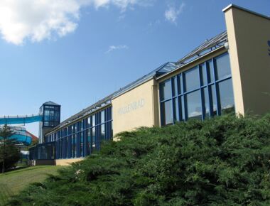 Außenansicht der Schwimmhalle in Kamenz. Hallenbad-Gebäude mit Wasserrutsche auf der linken Seite. Beispielbild für Bade- und Schwimmöglichkeiten in Kamenz.