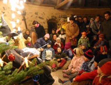 Märchenlesen zum Advents-Spectaculum in Kamenz - einem mittelalterlichen Erlebnisweeihnachtsmarkt. Zahlreiche Kinder sitzen mit ihren Eltern vor der Märchenerzählerin, die als Hexe verkleidet ist, und lauschen ihren Geschichten.