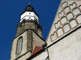 Blick von unten auf den Turm der Hauptkirche St. Marien mit blauem Himmel